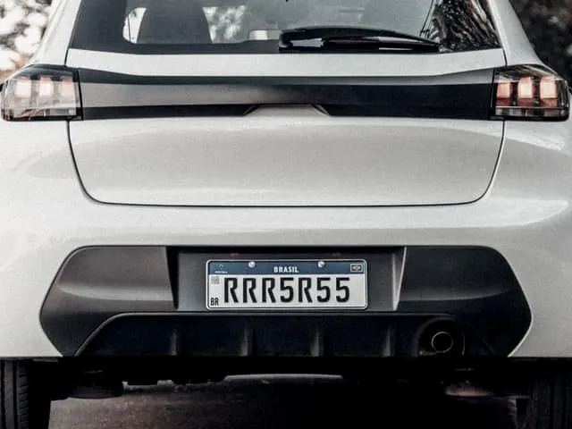 The rear of a hatchback parked at the edge of a quiet road, its plate visible.