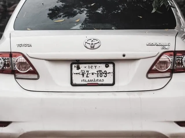 The rear of a saloon car parked on bare ground, its plate visible.
